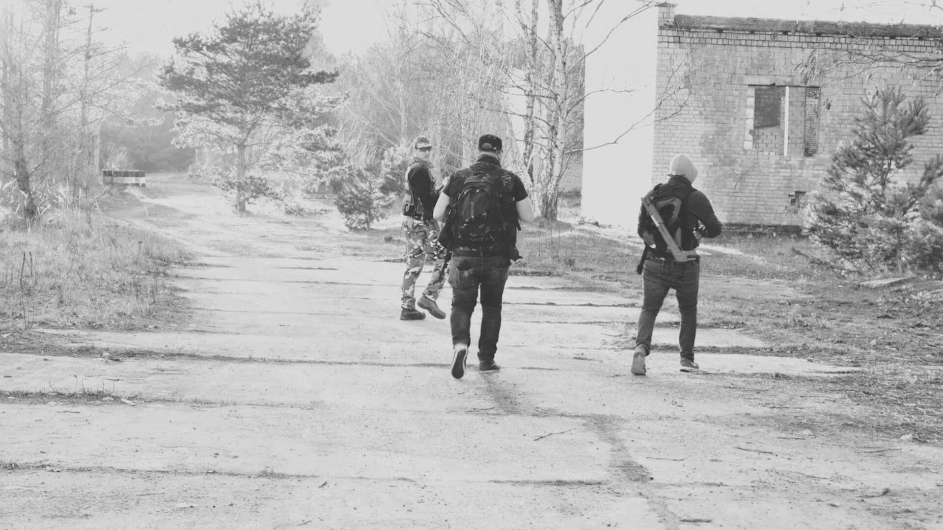 Drei Personen mit Ausrüstung in einer verlassenen Gegend beim Airsoft-Spiel.