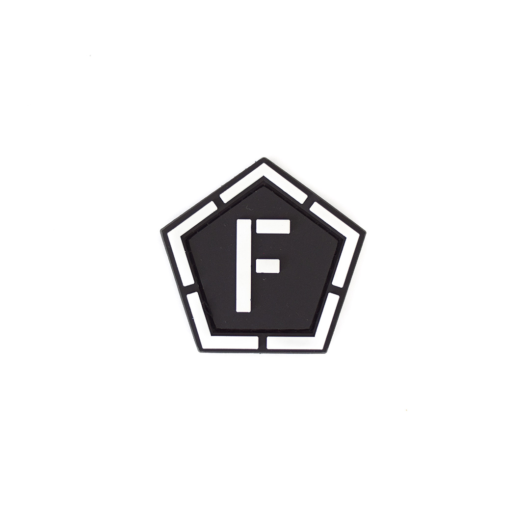 Schwarzes, fünfeckiges Airsoft-Patch mit weißem "F" in der Mitte.