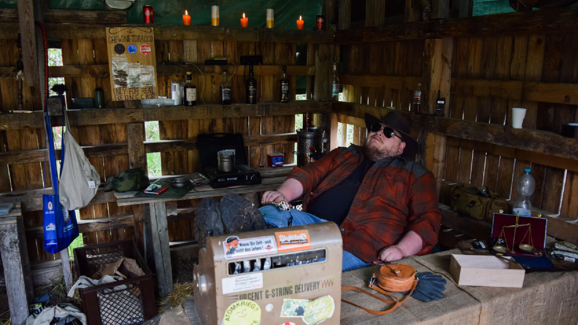 Person entspannt sich in rustikalem Holzraum mit Kerzen und diversen Gegenständen.