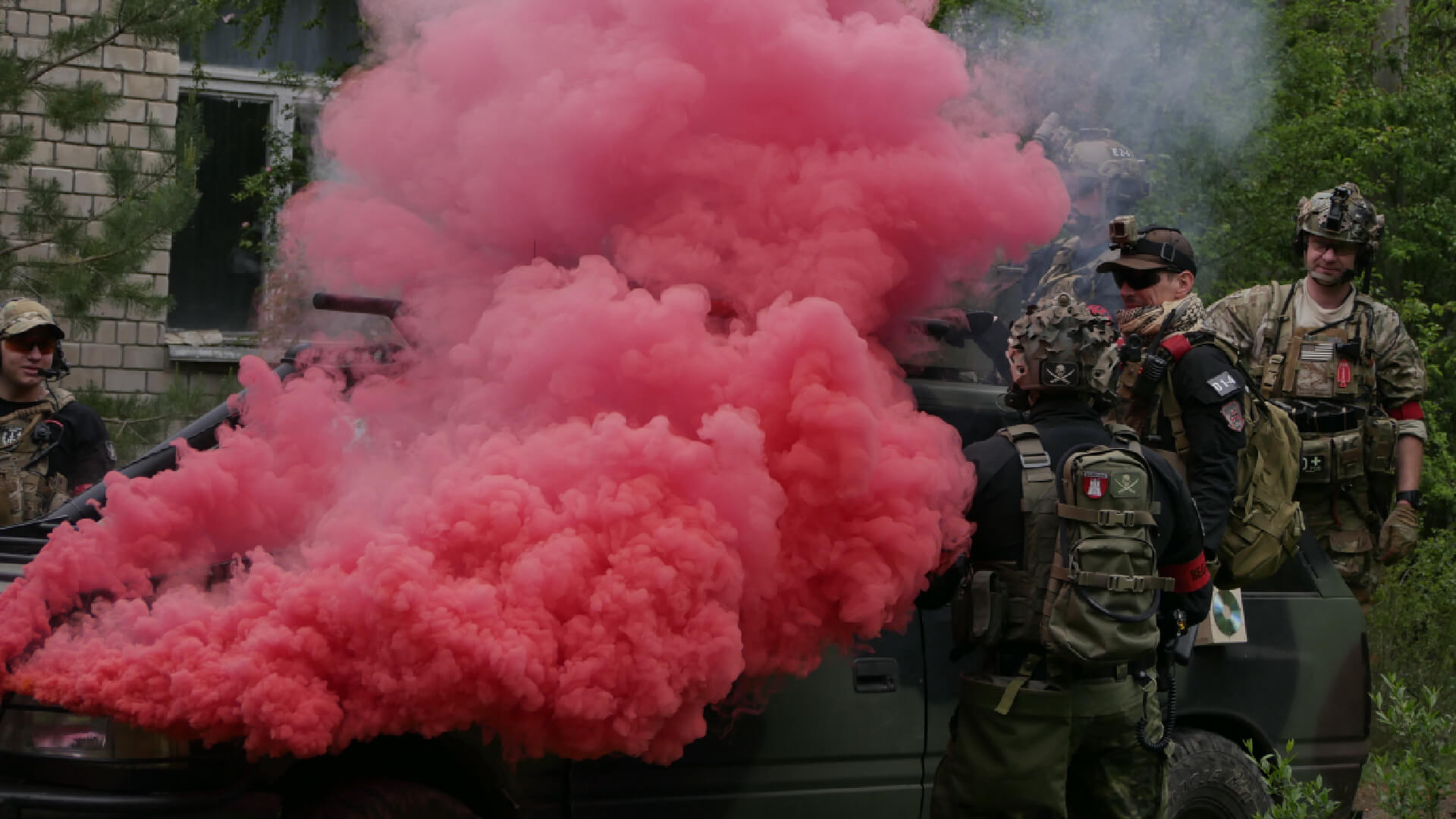 Airsoft-Spieler bei einem Einsatz mit rotem Rauch, ausgerüstet mit taktischer Kleidung und Ausrüstung.