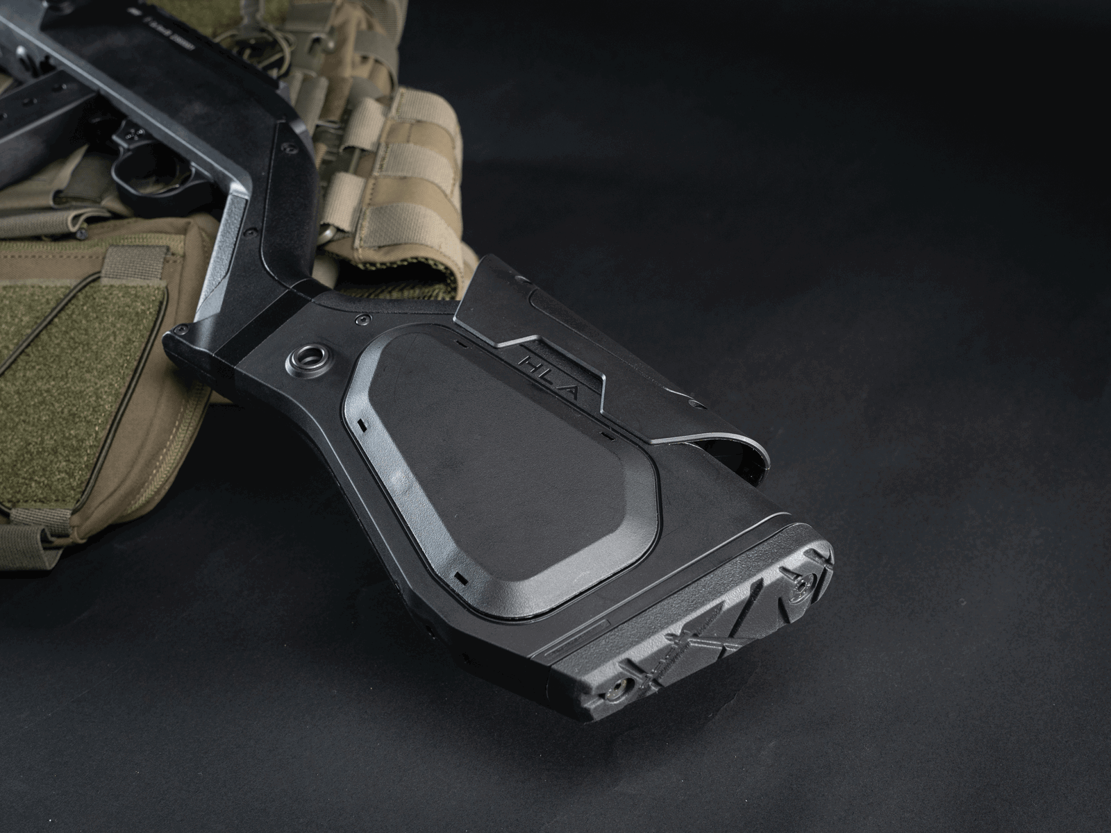 Schwarz-grüner Airsoft-Gewehrschaft und taktische Weste auf dunklem Hintergrund.