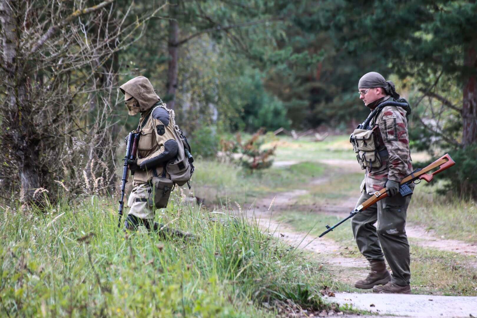 Zwei Airsoft-Spieler im Tarnoutfit mit Gewehren im Wald unterwegs.