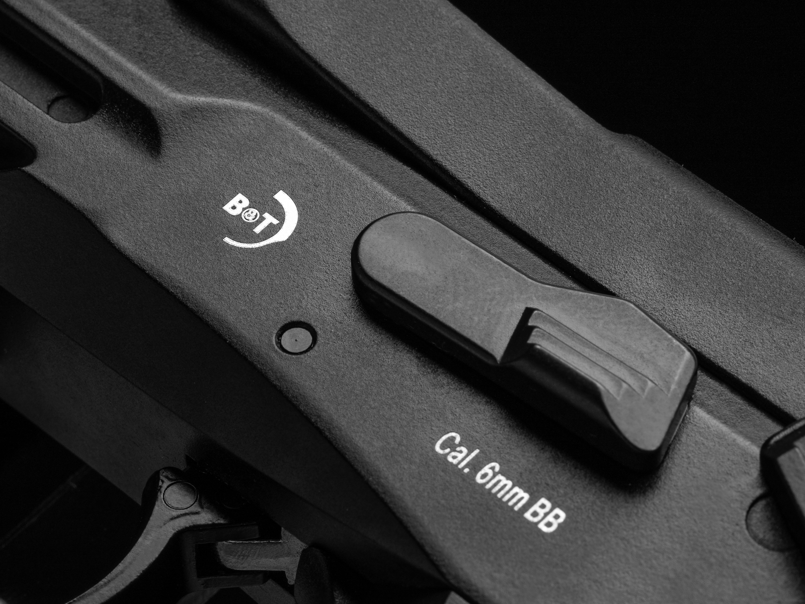 Nahaufnahme eines Airsoft-Gewehrs, zeigt "B&T" Markierung und Kaliberangabe 6mm BB auf schwarzem Gehäuse.