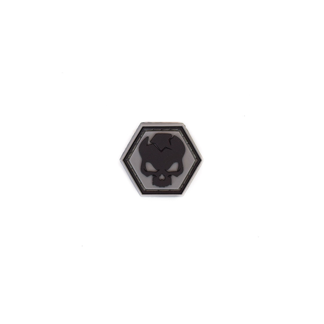 Schwarzes hexagonales Airsoft-Patch mit Totenkopfdesign auf weißem Hintergrund.