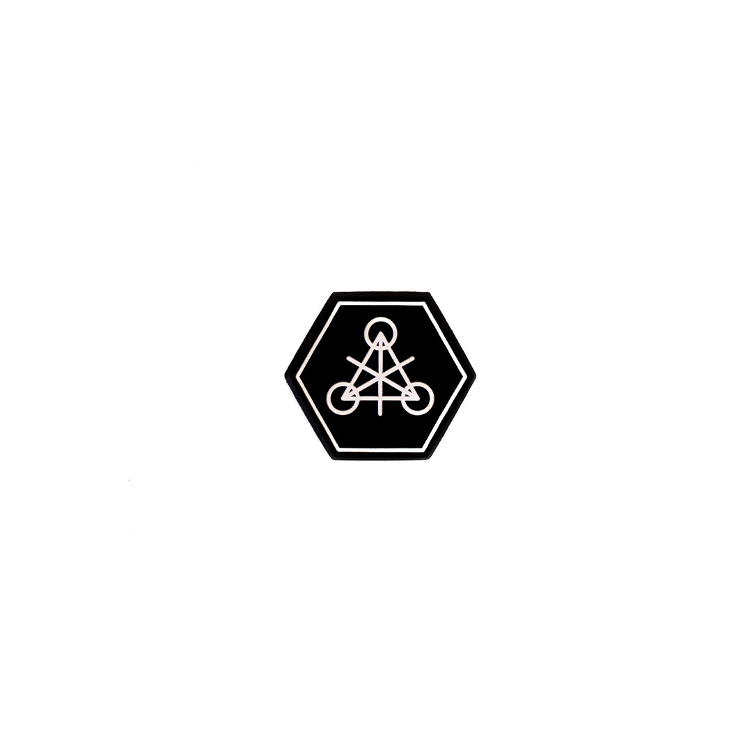 Hexagonaler Aufnäher mit geometrischem Symbol auf schwarzem Hintergrund.