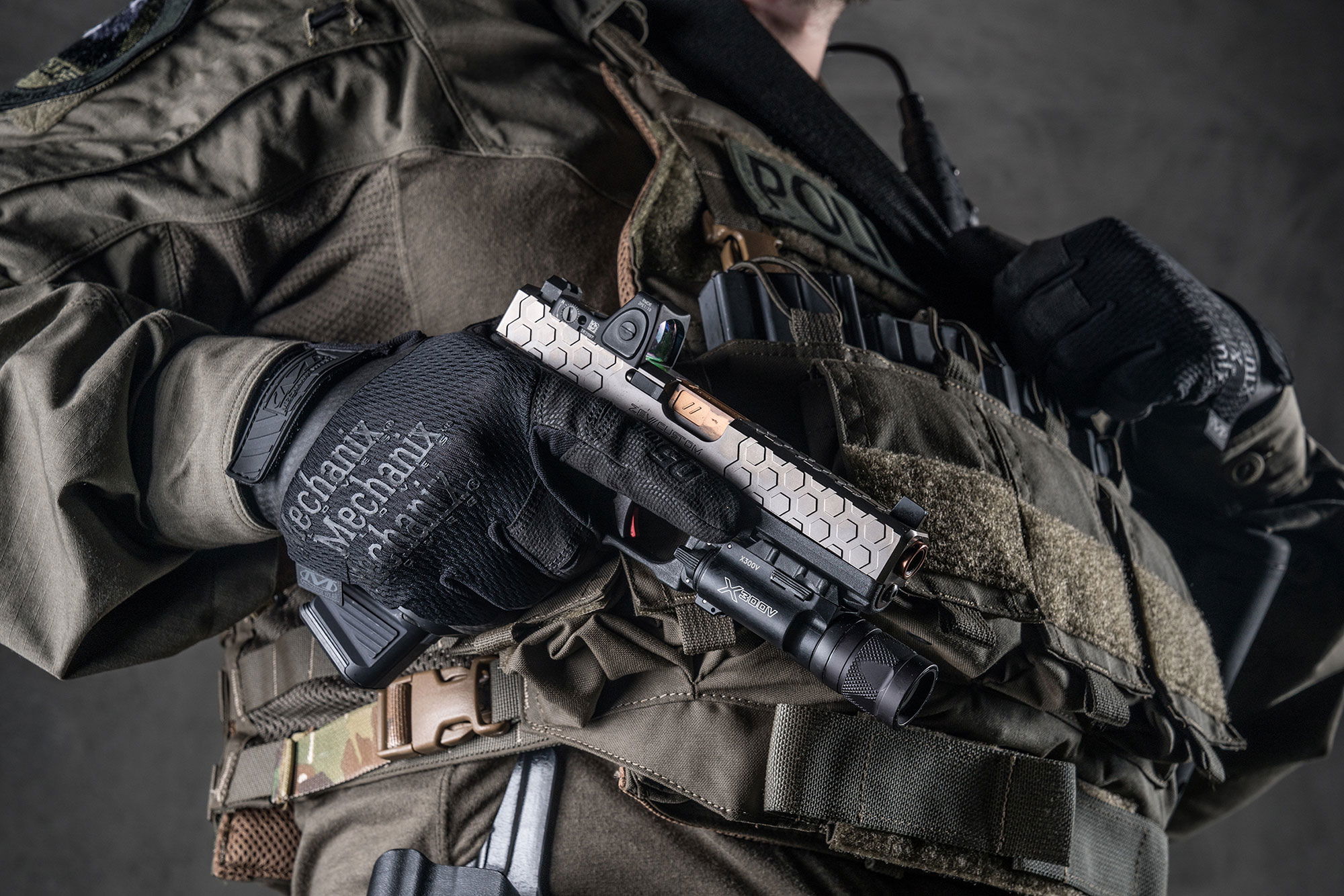 Mechanix Handschuhe Specialty 0.5mm Covert Taktische Ausrüstung mit Pistole und Lampe, getragen von einer Person in militärischem Outfit.