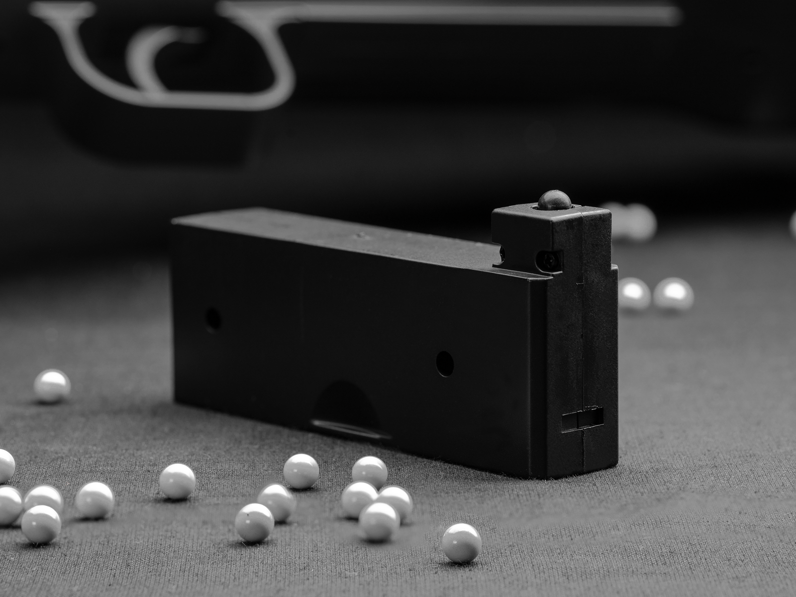 Airsoft-Boxmagazin mit weißen BB-Kugeln auf schwarzem Hintergrund.