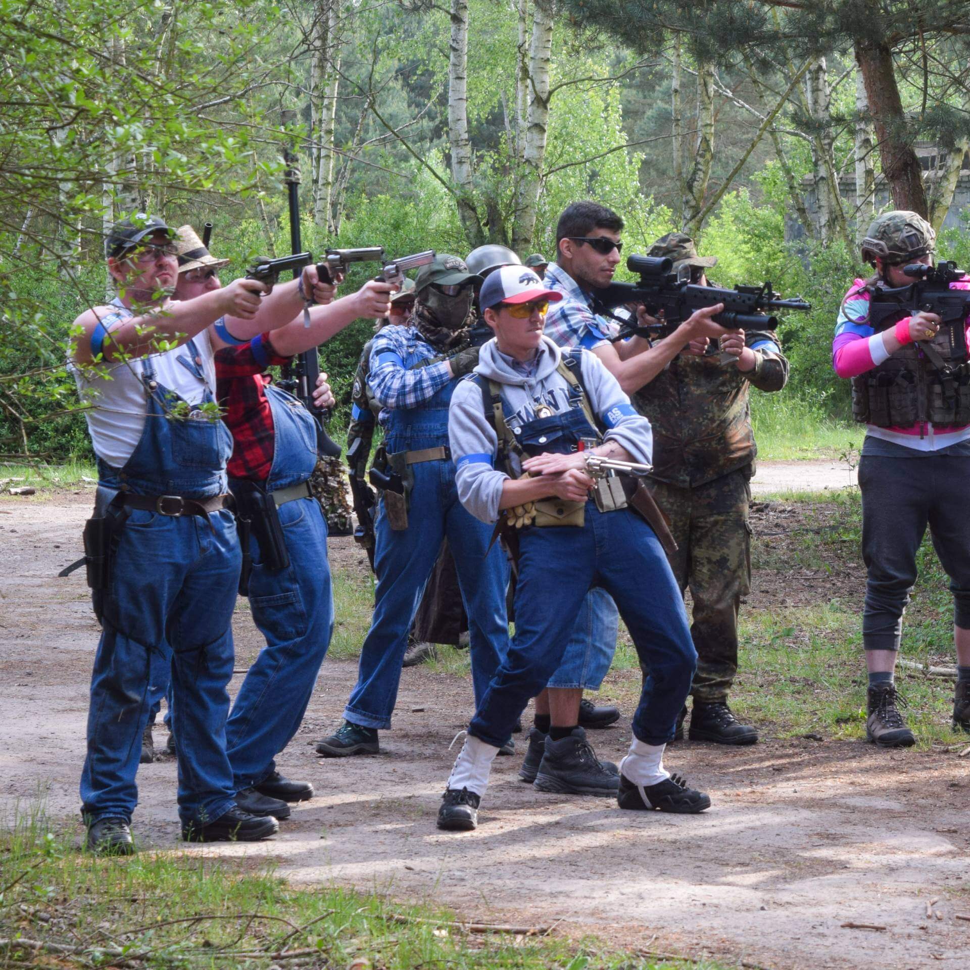 Airsoft-Team in Tarnkleidung mit verschiedenen Waffen im Wald, bereit für ein Szenario.