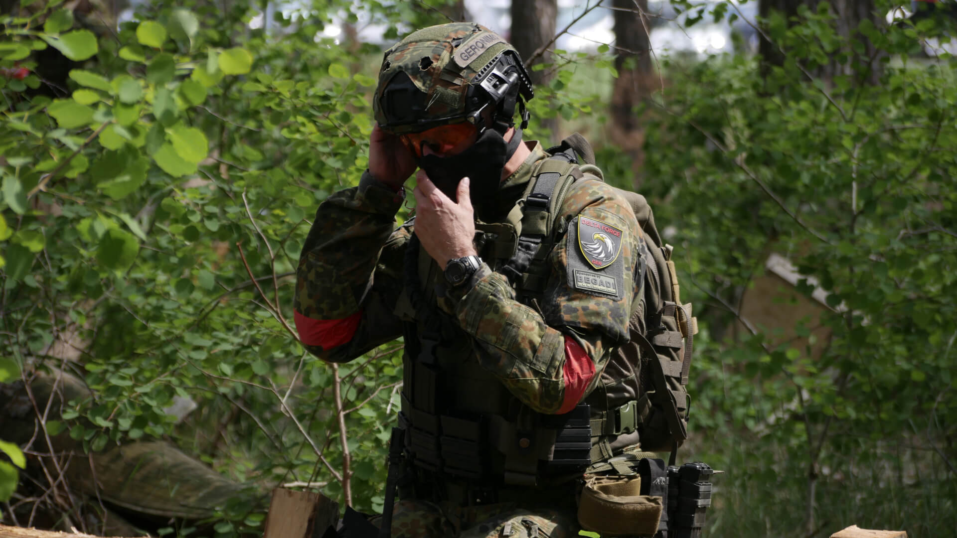 Airsoft-Spieler in Tarnkleidung, passt im Wald sein Visier an.