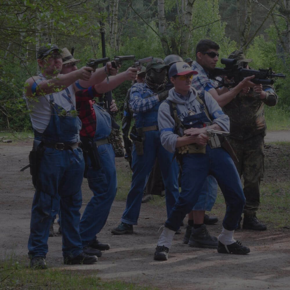 Gruppe von Airsoft-Spielern in Freizeitkleidung zielt mit Gewehren im Wald.