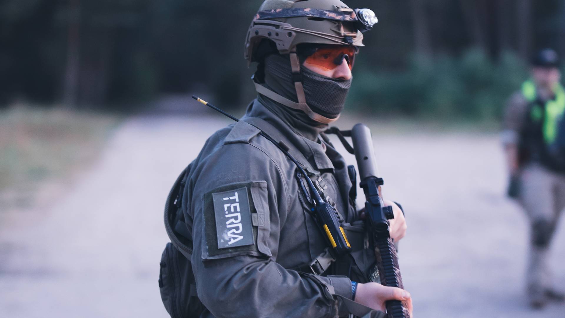 Airsoft-Spieler in Tarnkleidung mit Gewehr und Helm im Wald.