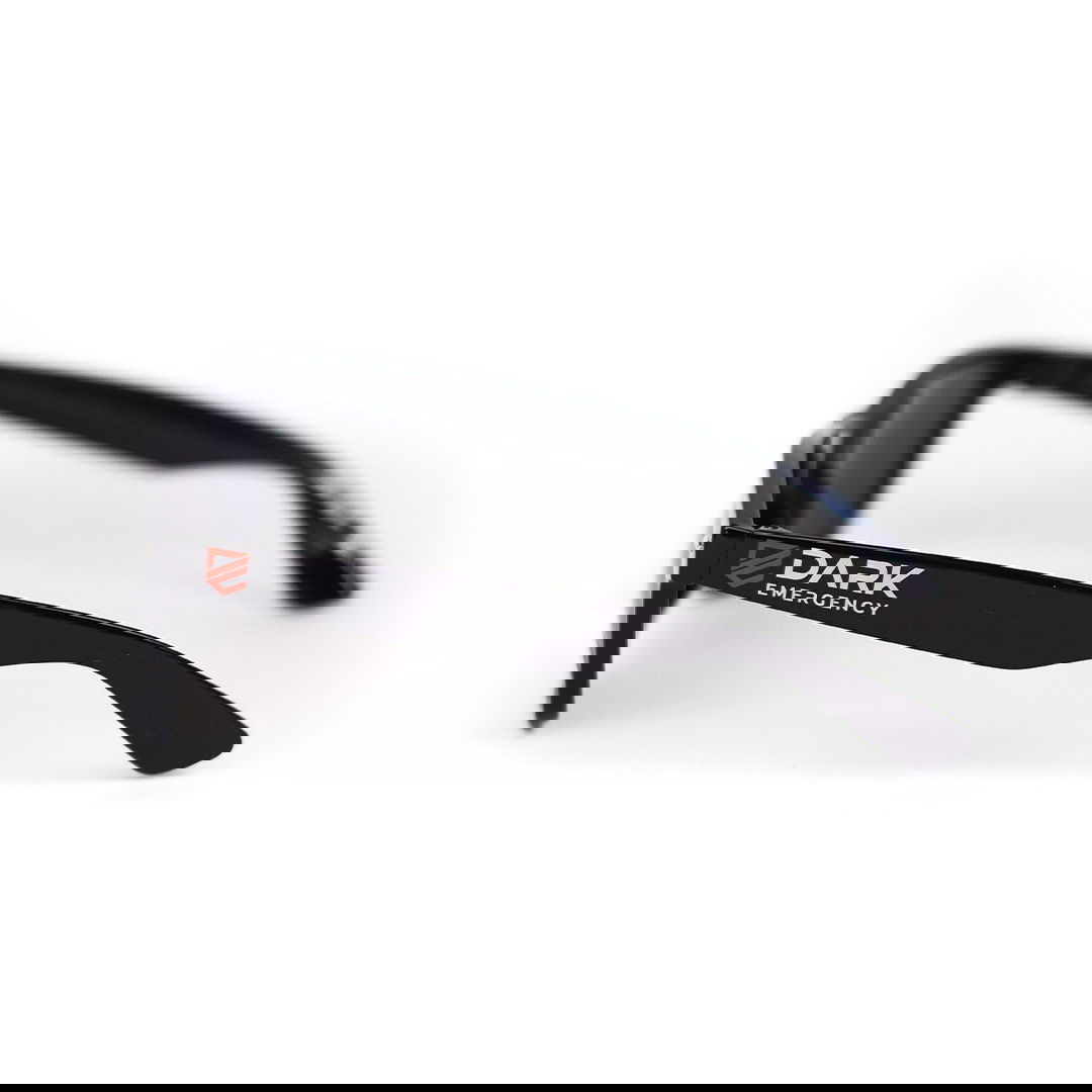 Dark Emergency Sonnenbrille  Schwarze Sonnenbrille mit "Dark Emergency"-Logo auf dem Bügel, seitlich abgebildet.
