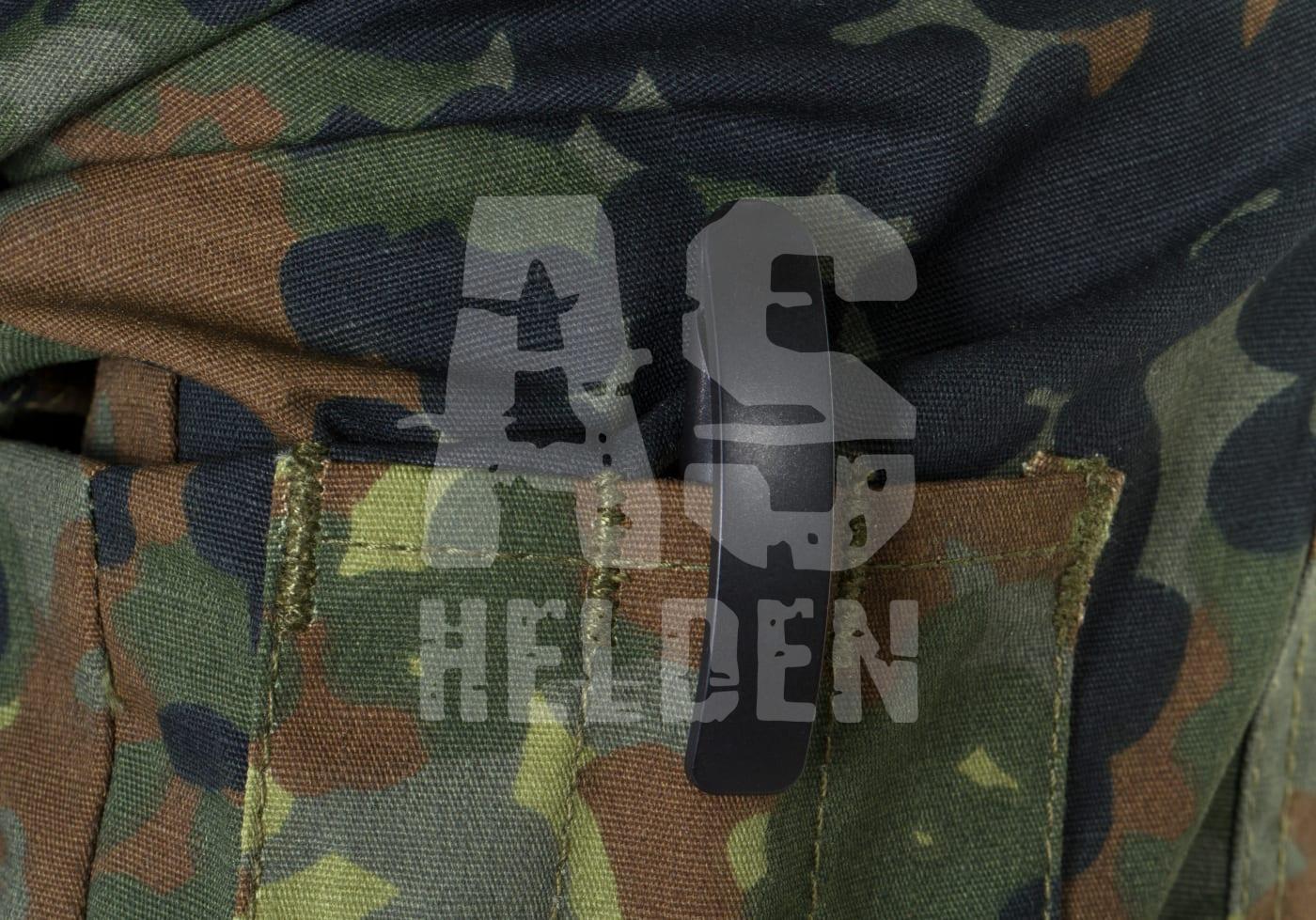 Ausrüstungstasche mit Tarnmuster und Clip auf grünem Stoff.