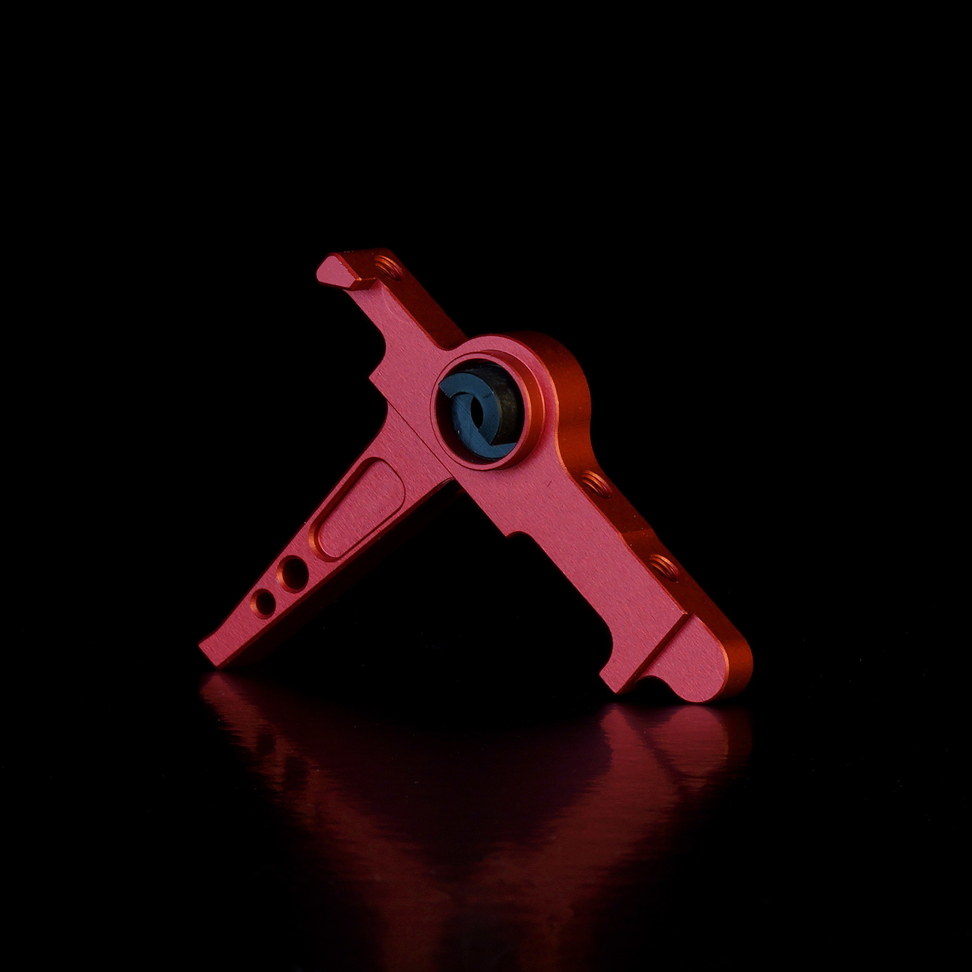 Roter CNC-gefräster Airsoft-Abzug auf schwarzem Hintergrund.