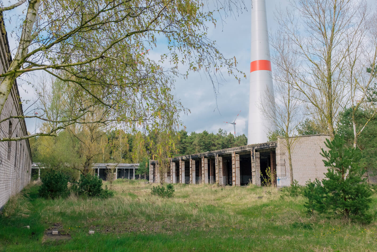 Verlassene Gebäude in grüner Landschaft, Chimney im Hintergrund, ideal für Airsoftspiele.