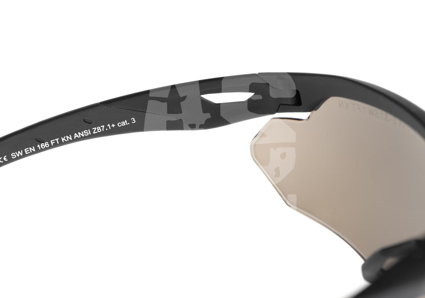 Nahaufnahme einer taktischen Brille mit Camouflage-Muster, Sicherheitsnormen auf dem Bügel.