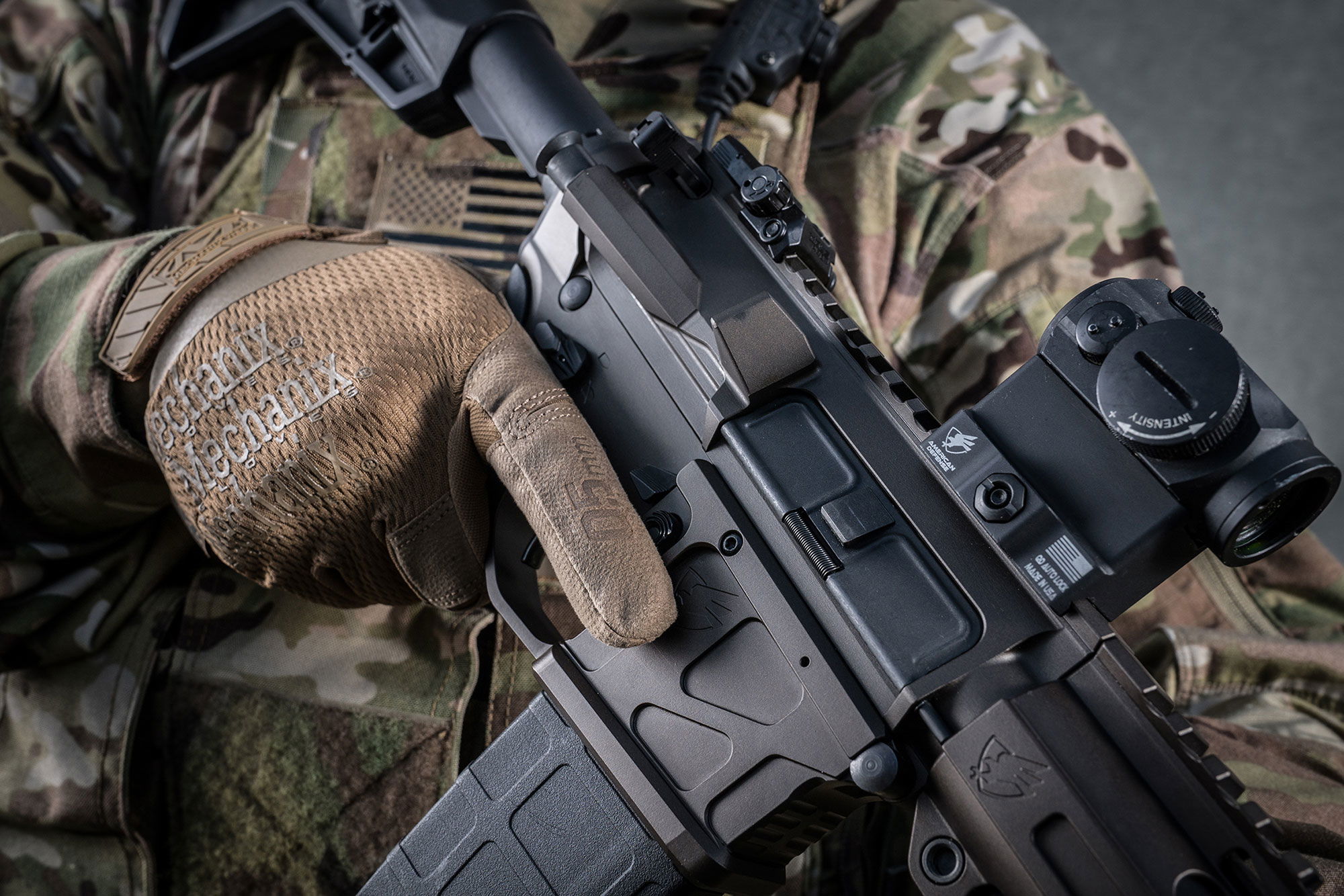 Person in Tarnkleidung hält Airsoft-Gewehr und trägt Mechanix-Handschuhe.