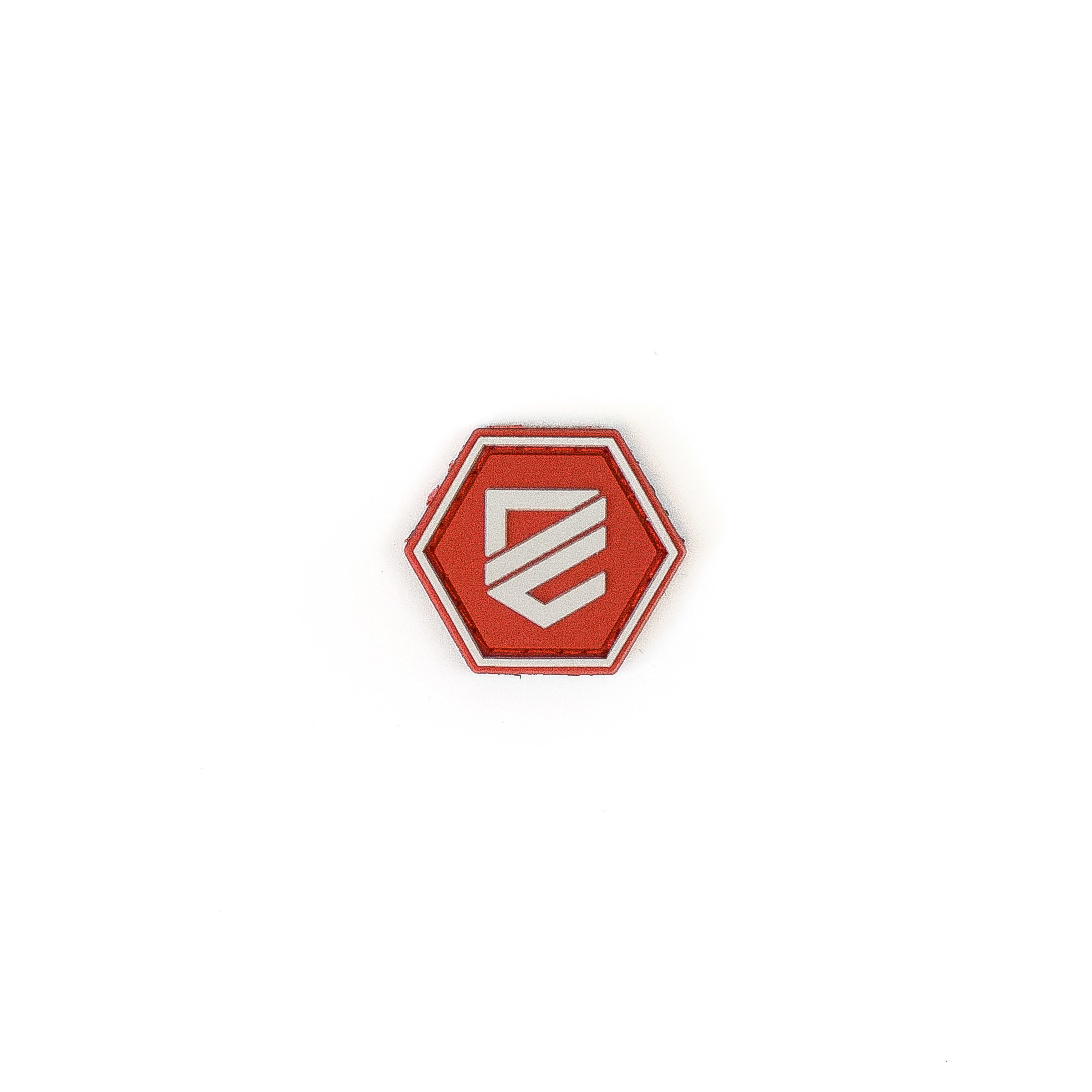 Rotes, sechseckiges Airsoft-Patch mit weißem Logo auf weißem Hintergrund.