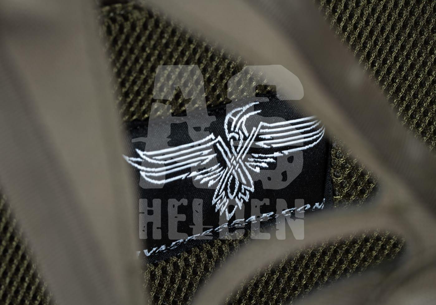 Nahaufnahme eines Airsoft-Patchs mit Flügelmotiv auf olivgrünem Stoffhintergrund.