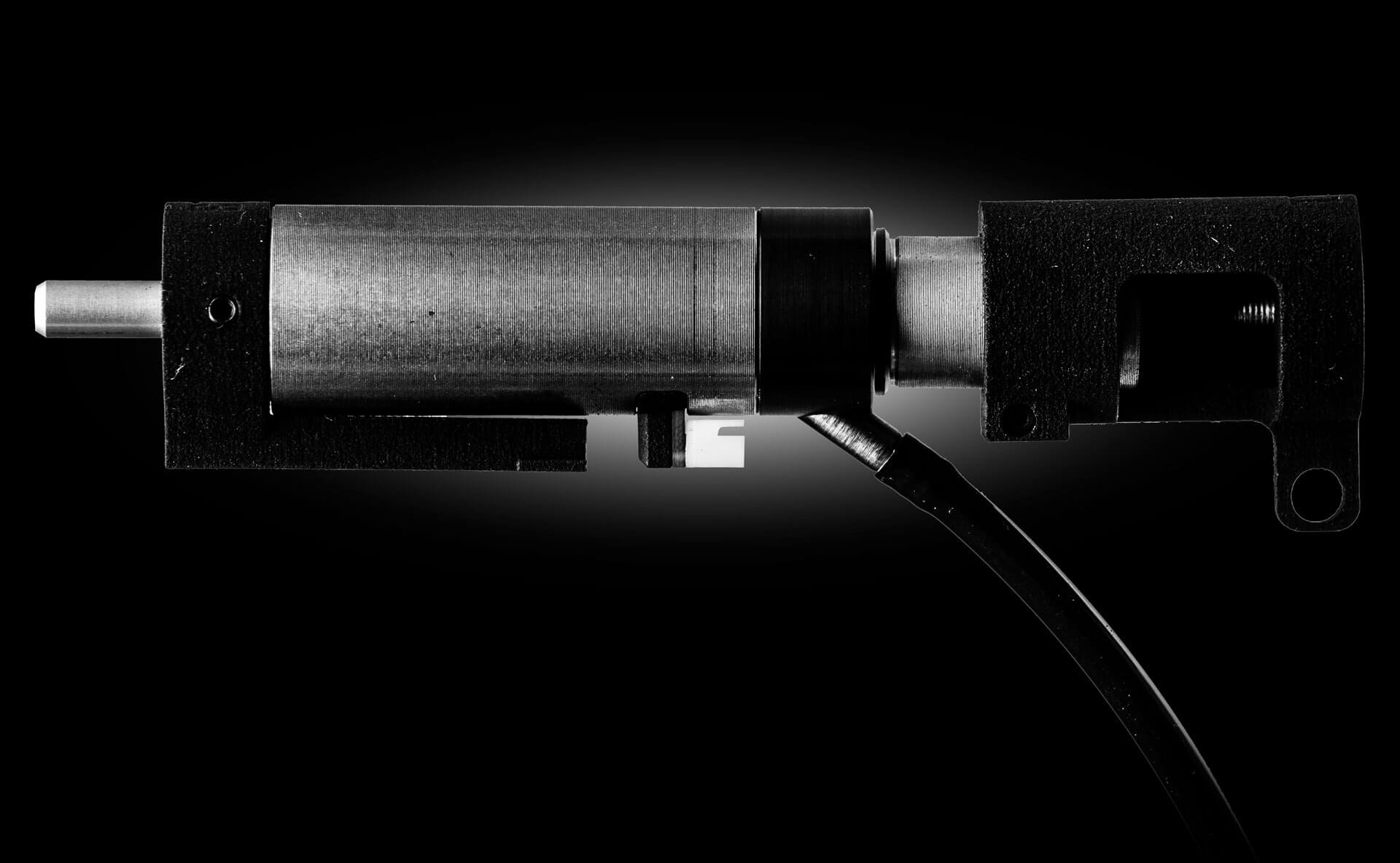 Airsoft Hi-Capa Rückstoßsystem, metallisch, seitlich, auf schwarzem Hintergrund.