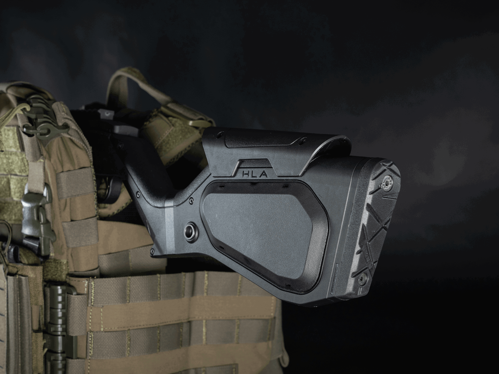 Schwarzer taktischer Airsoft-Schulterkolben auf Tarn-Plattenträger montiert.