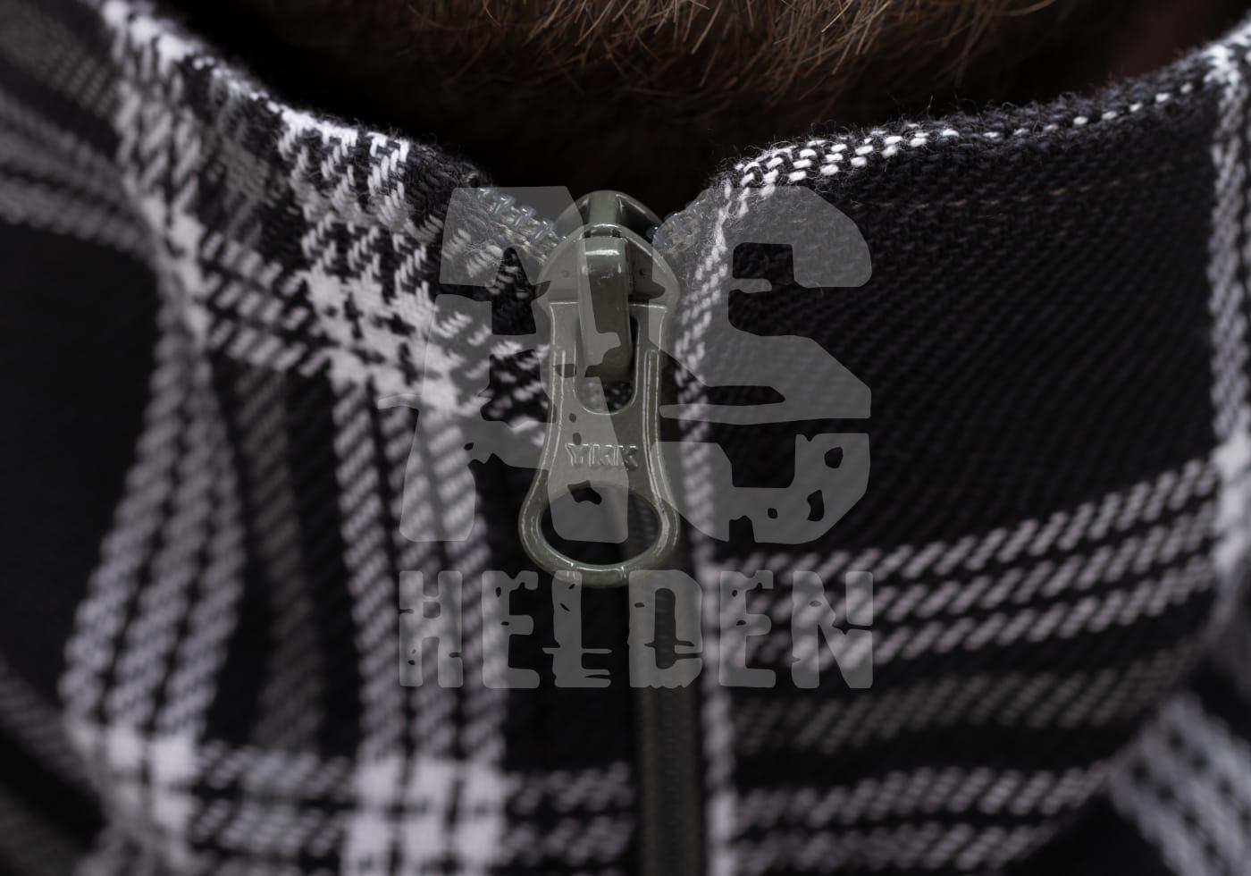 Nahaufnahme eines karierten Stoffes mit Reißverschluss und Airsoft Helden-Logo im Vordergrund.