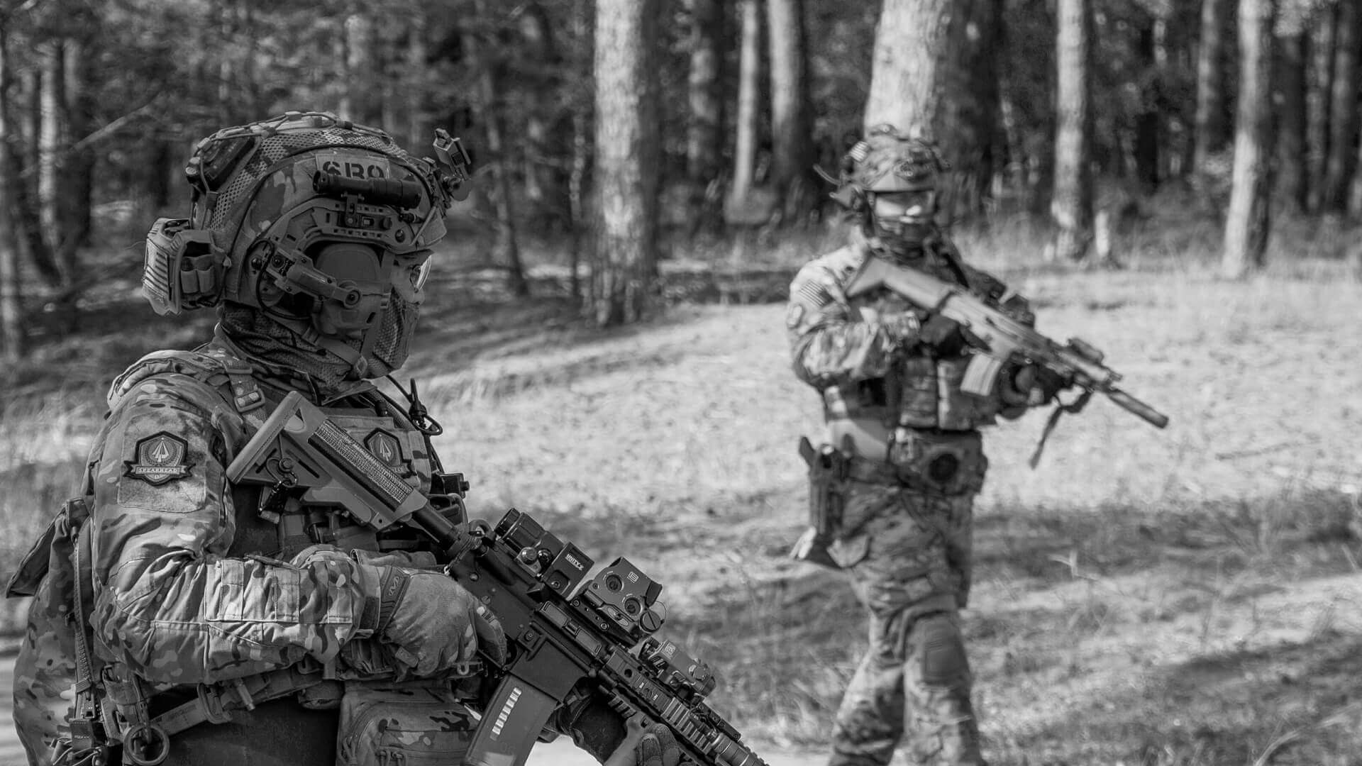 Zwei Airsoft-Spieler in taktischer Ausrüstung und Tarnkleidung im Wald. Beide halten Airsoft-Waffen.