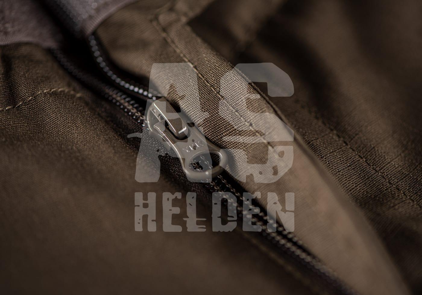 Nahaufnahme eines olivgrünen Reißverschlusses auf taktischem Stoff, Logo von Airsoft Helden im Hintergrund.