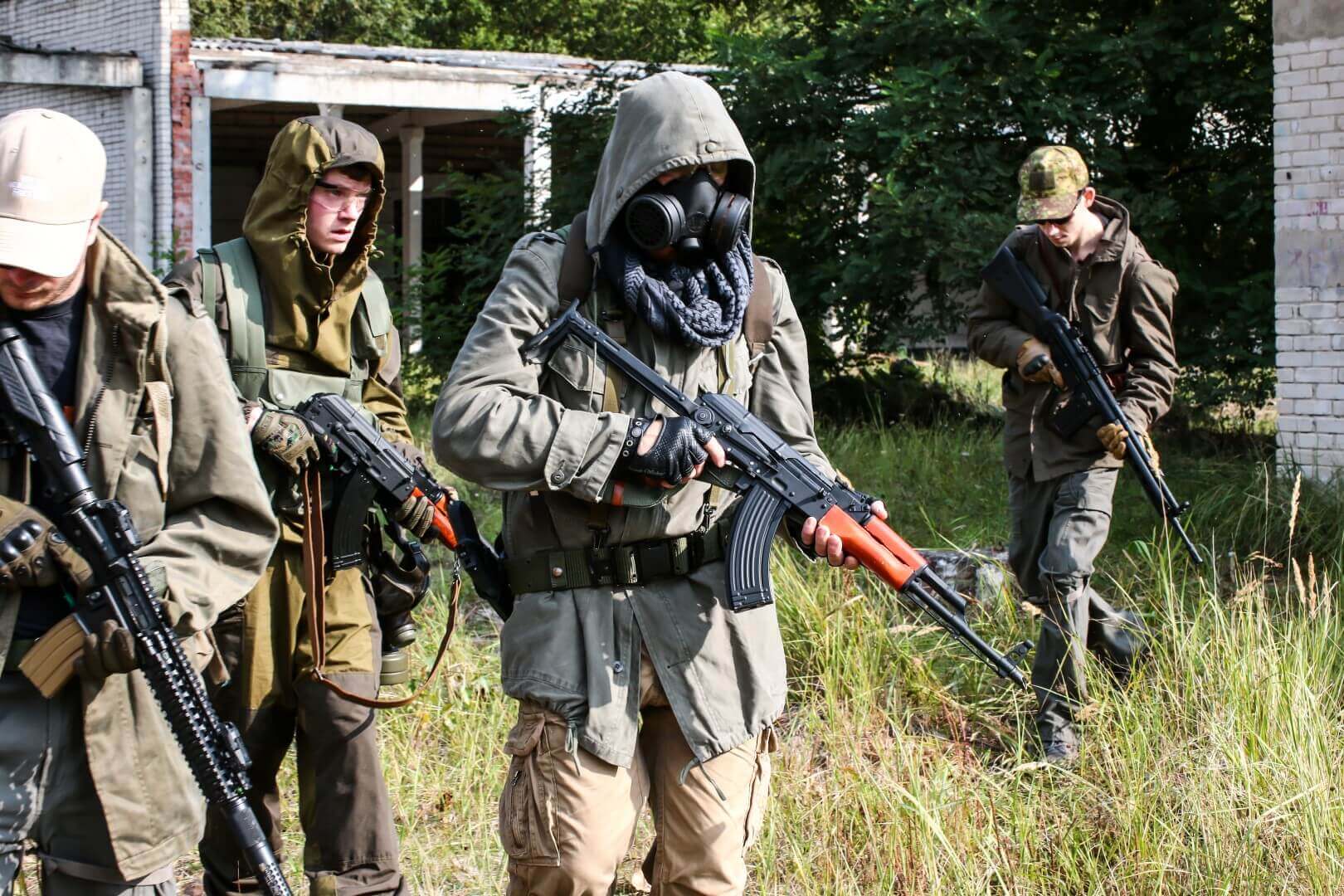 Vier Airsoft-Spieler in taktischer Ausrüstung mit Gewehren im Freien.