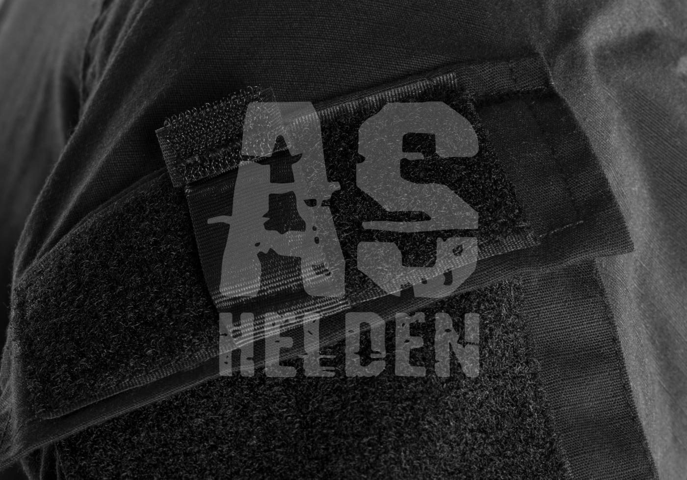 Schwarzes Stoffstück mit Klettverschluss und Logo-Aufdruck "AS Helden".