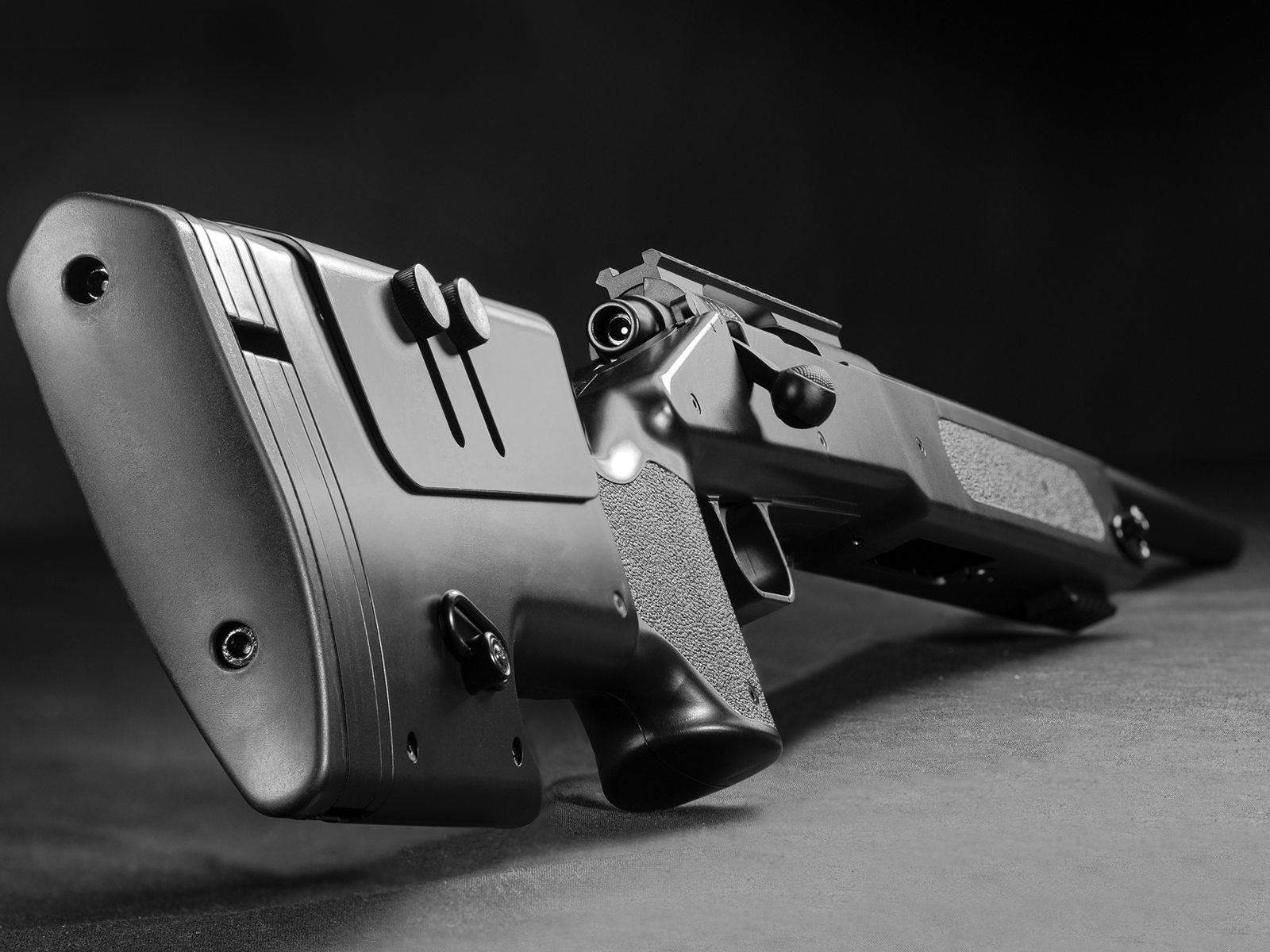 Airsoft-Gewehr mit verstellbarem Schaft und taktiler Oberfläche, schräg von unten fotografiert.