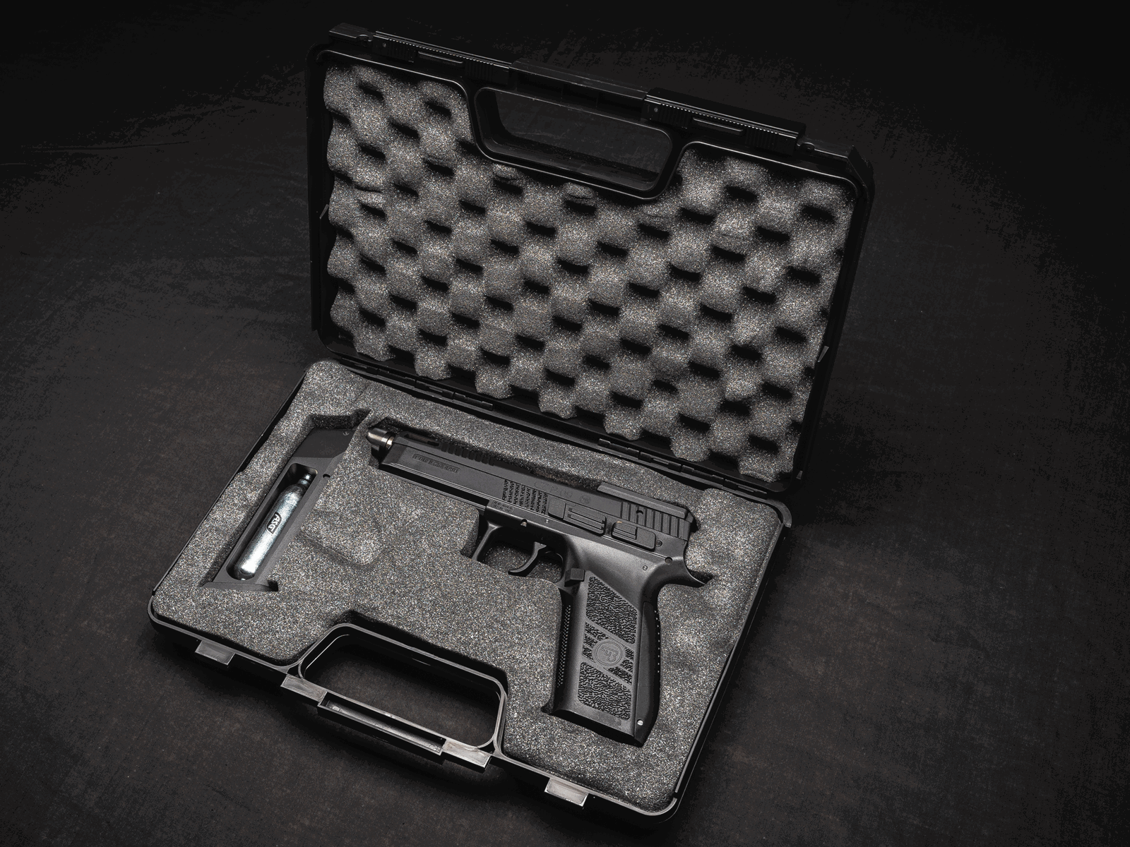 Airsoft-Pistole in offenem Koffer mit Schaumstoffauskleidung, CO2-Kapsel sichtbar.