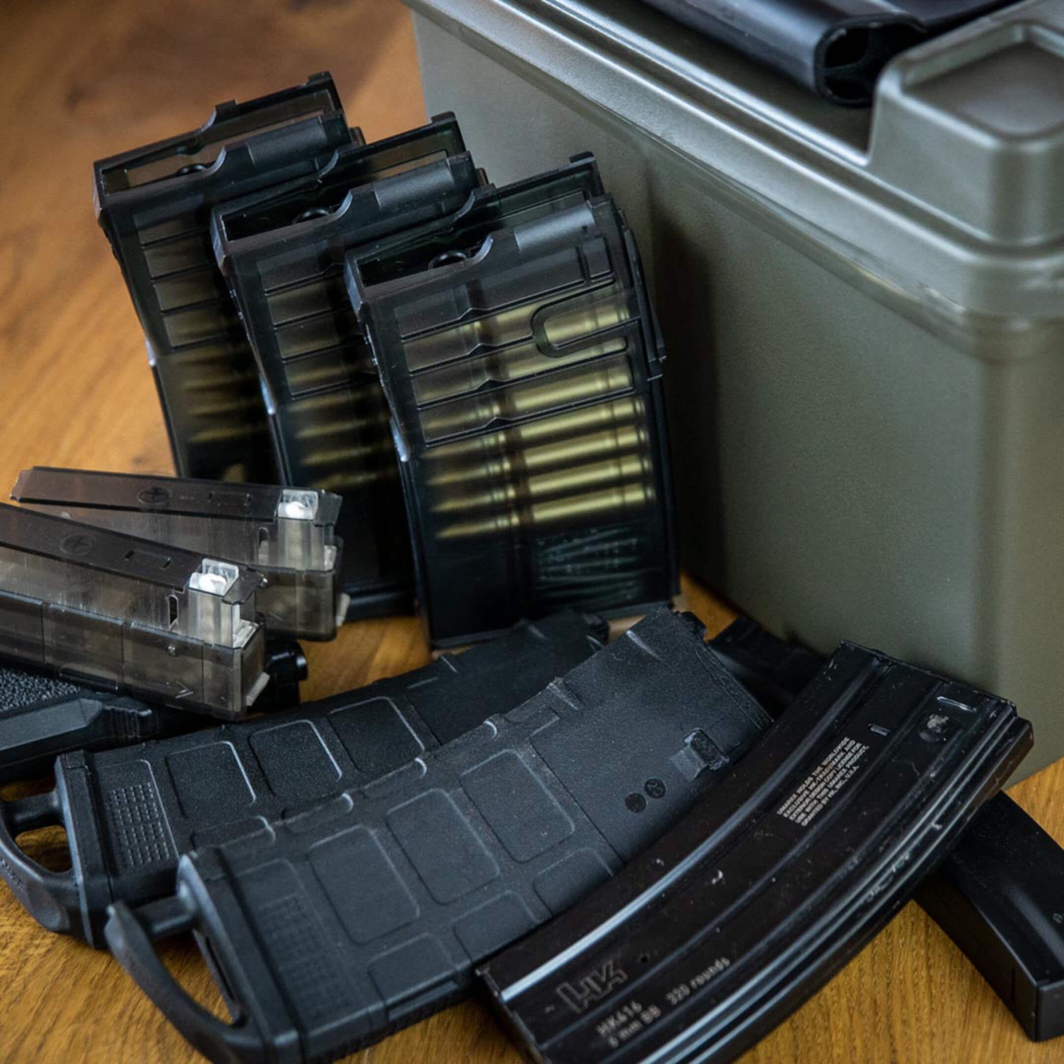 Airsoft-Magazine und Munitionsbox auf Holztisch, bereit für Spiel oder Training.