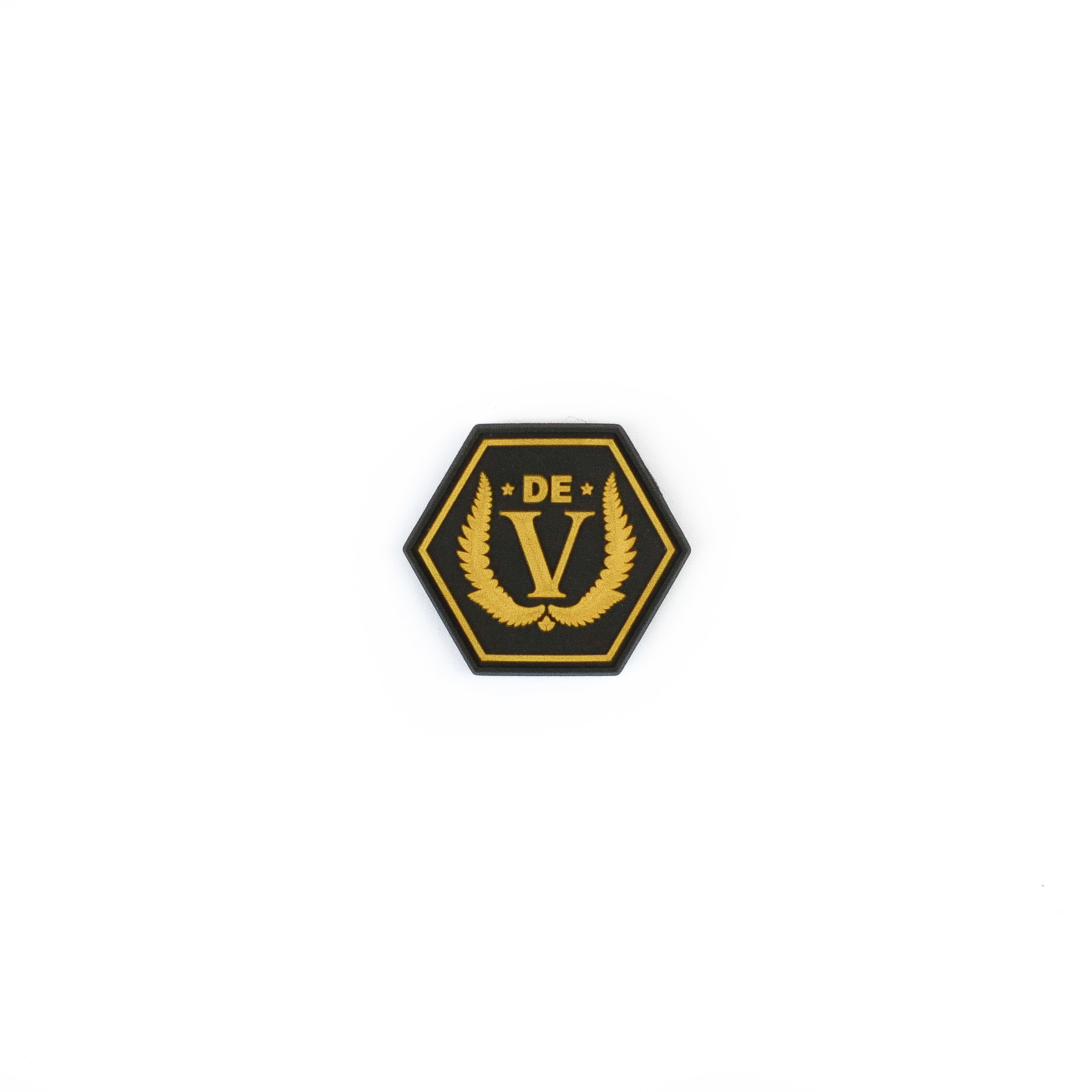 Hexagonaler Aufnäher mit goldenem "DE V" und Lorbeerkranz auf schwarzem Hintergrund.
