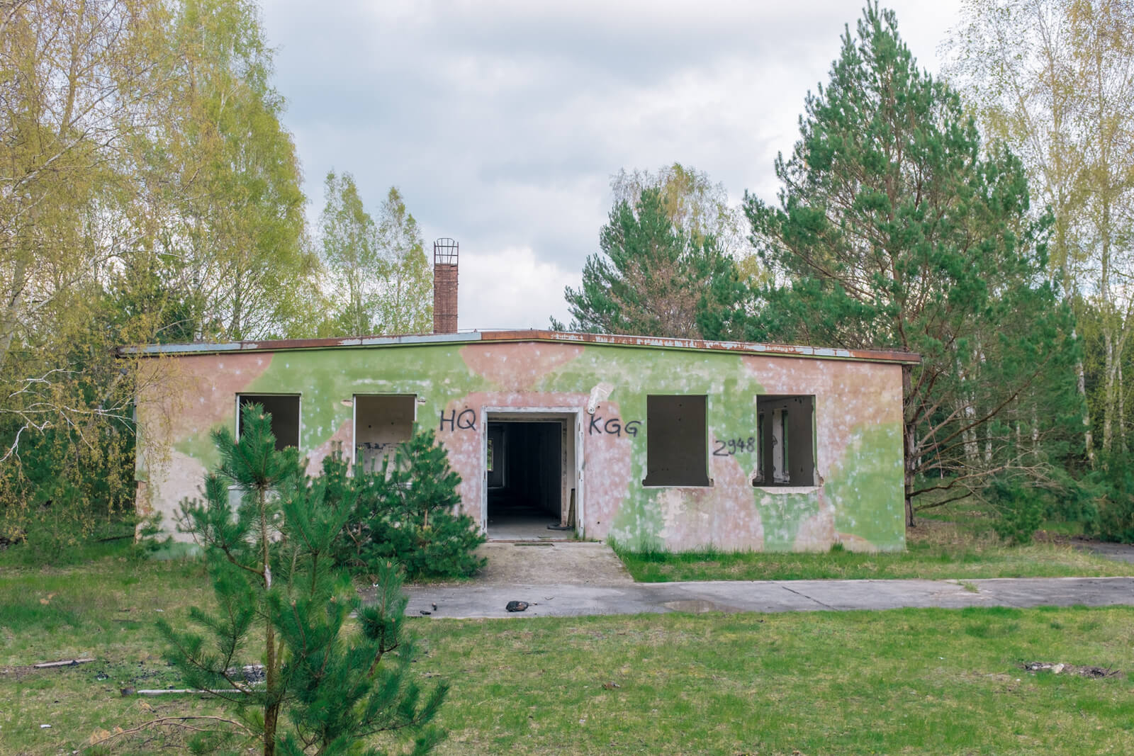 Verlassenes Gebäude im Wald mit Tarnfarben bemalt, geeignet für Airsoft-Spiele.