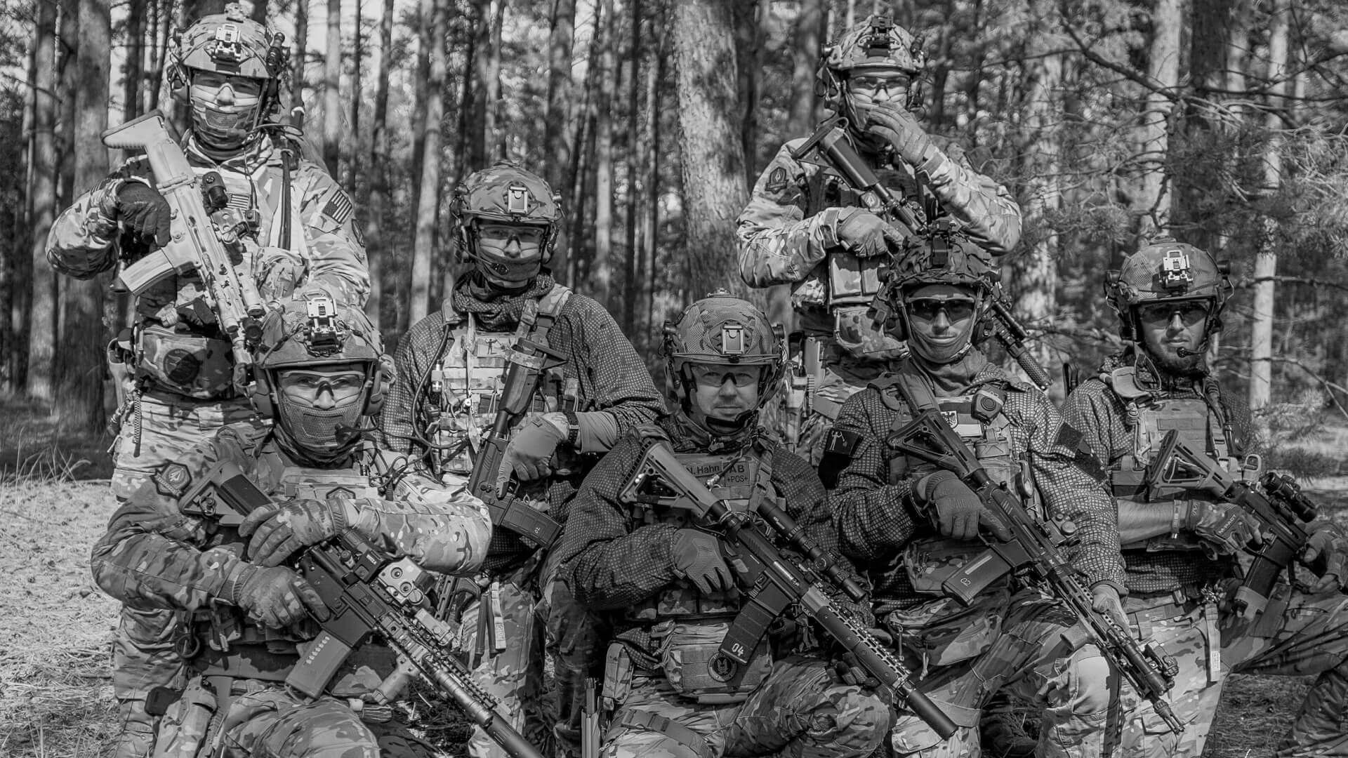 Airsoft-Team in Tarnkleidung im Wald, posierend mit Gewehren und taktischer Ausrüstung.