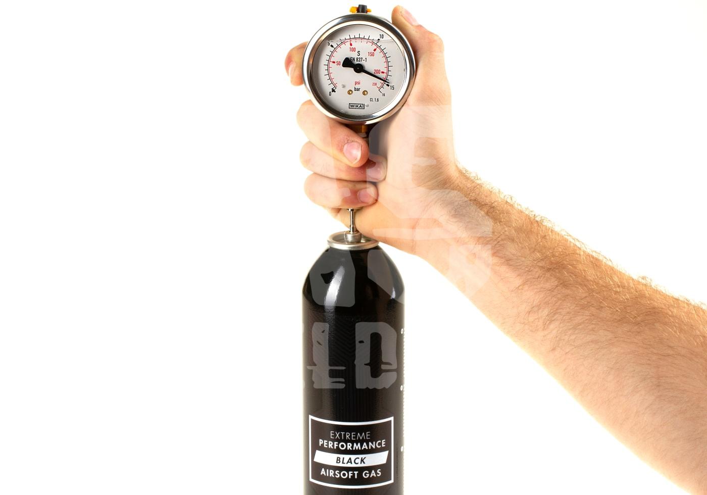 Hand hält Airsoft-Gasflasche mit Druckmesser für Leistungsüberprüfung.