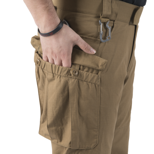 MBDU® Trousers - NyCo Ripstop - MultiCam Black™ Hand steckt in multifunktionaler, brauner Hosentasche mit Karabiner. Ideal für Airsoft-Zubehör.